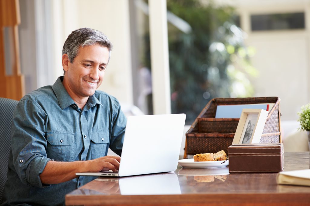 A senior stock trader making a satisfying trade on his laptop