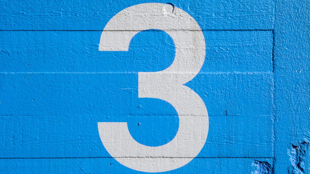 a white number 3 painted on a blue wall